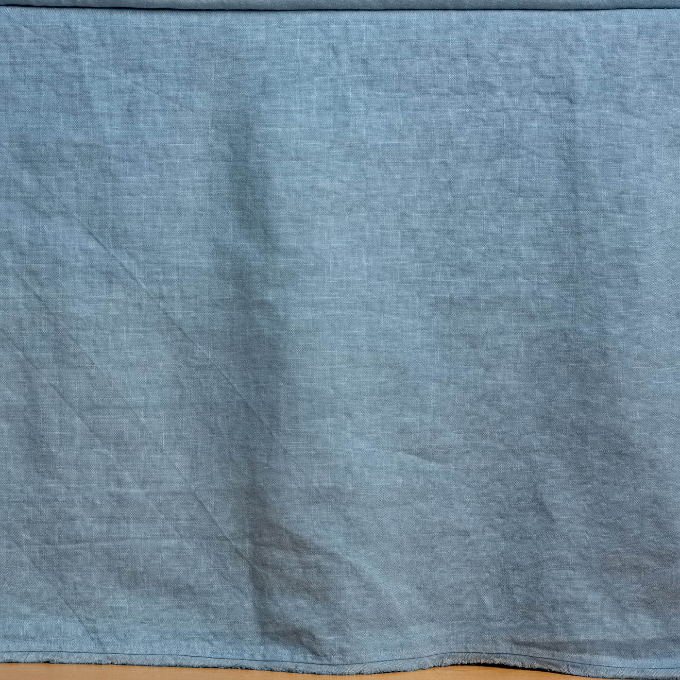 Close-up of Bella Notte Austin bed skirt in Tahoe Blue, showing washed linen texture and hem.