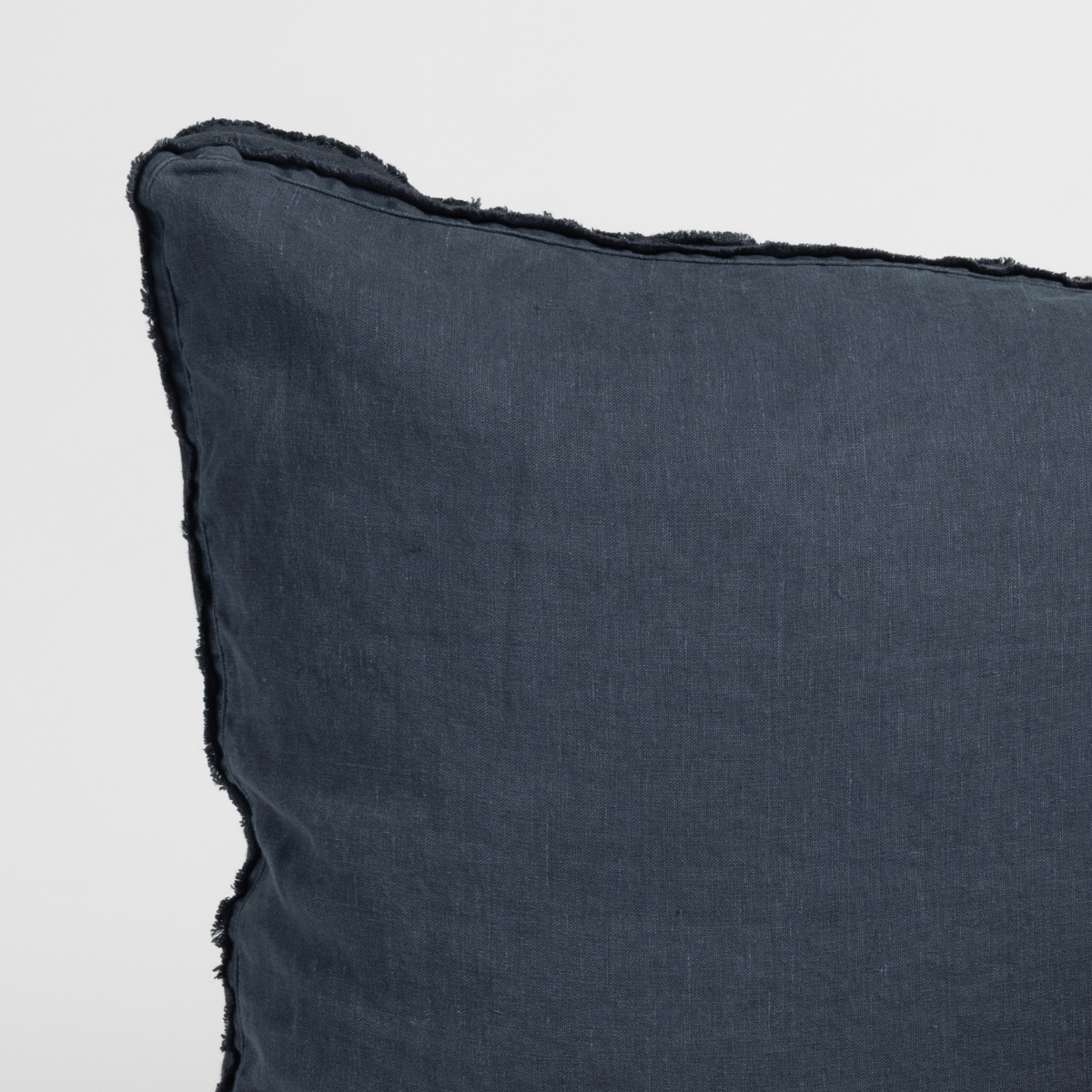 Corner detail of Bella Notte Austin sham in Slate, showing frayed linen edge trim.