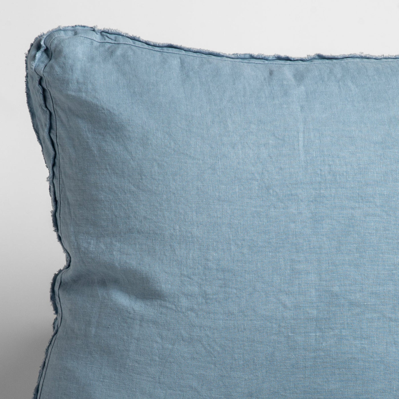 Close-up of Austin sham corner in Tahoe Blue, showing relaxed linen weave and frayed edge trim.