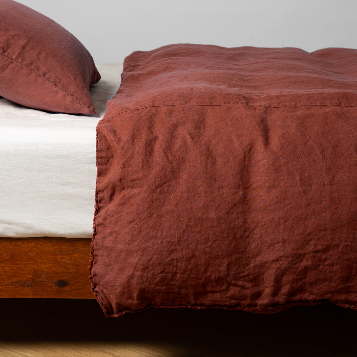 Relaxed linen duvet cover in Autumn draped over a wood-frame bed with matching pillowcase.