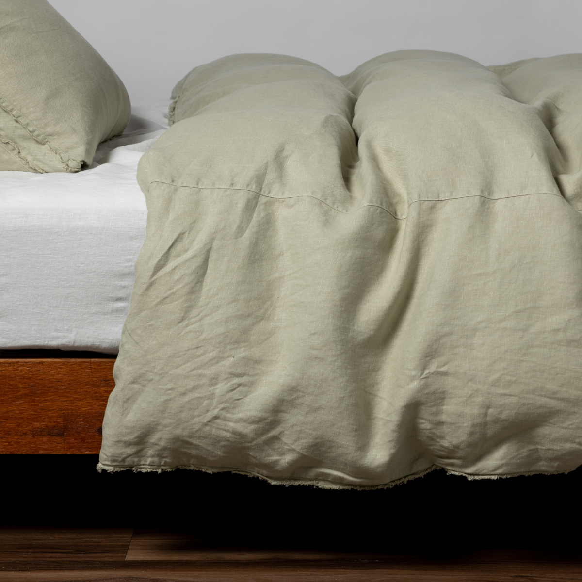 Desert Sage linen duvet cover draped over bed, relaxed rumpled texture with matching pillowcases.