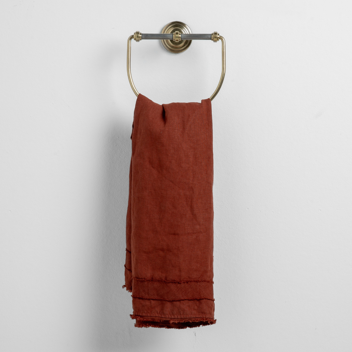Autumn linen guest towel draped on a brass ring holder, showing fringe hem detail.