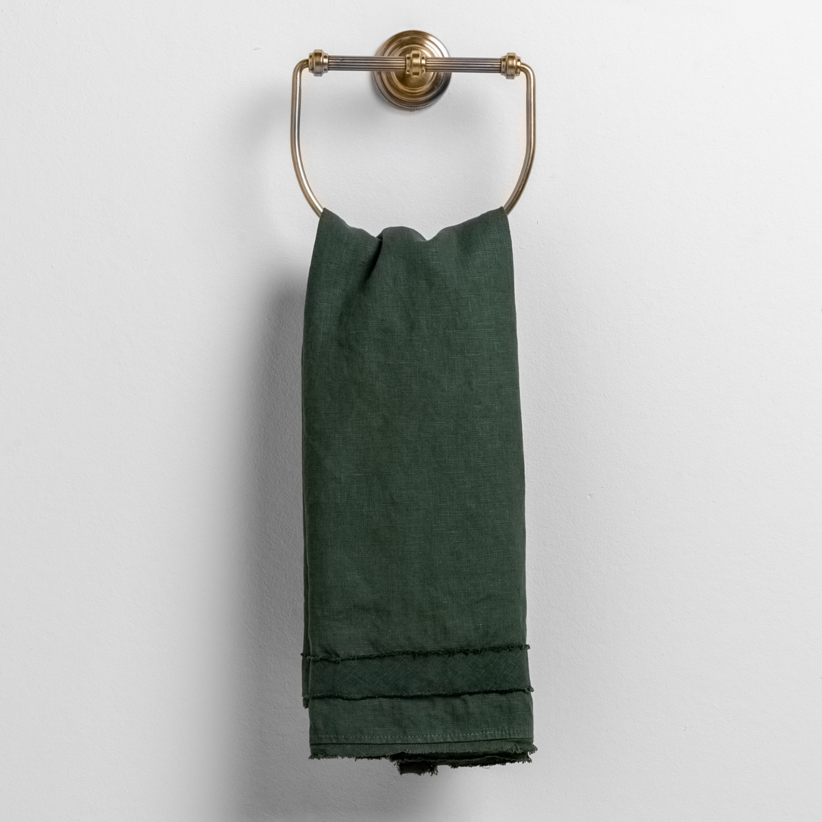 Juniper guest towel draped over brass ring, showing frayed hem detail.