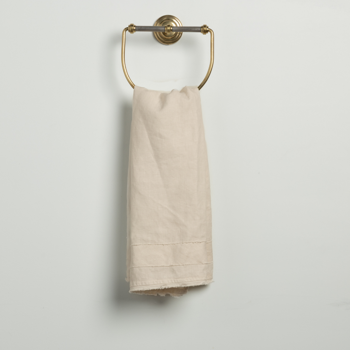 Bella Notte Austin guest towel in Natural, folded on a brass ring holder.