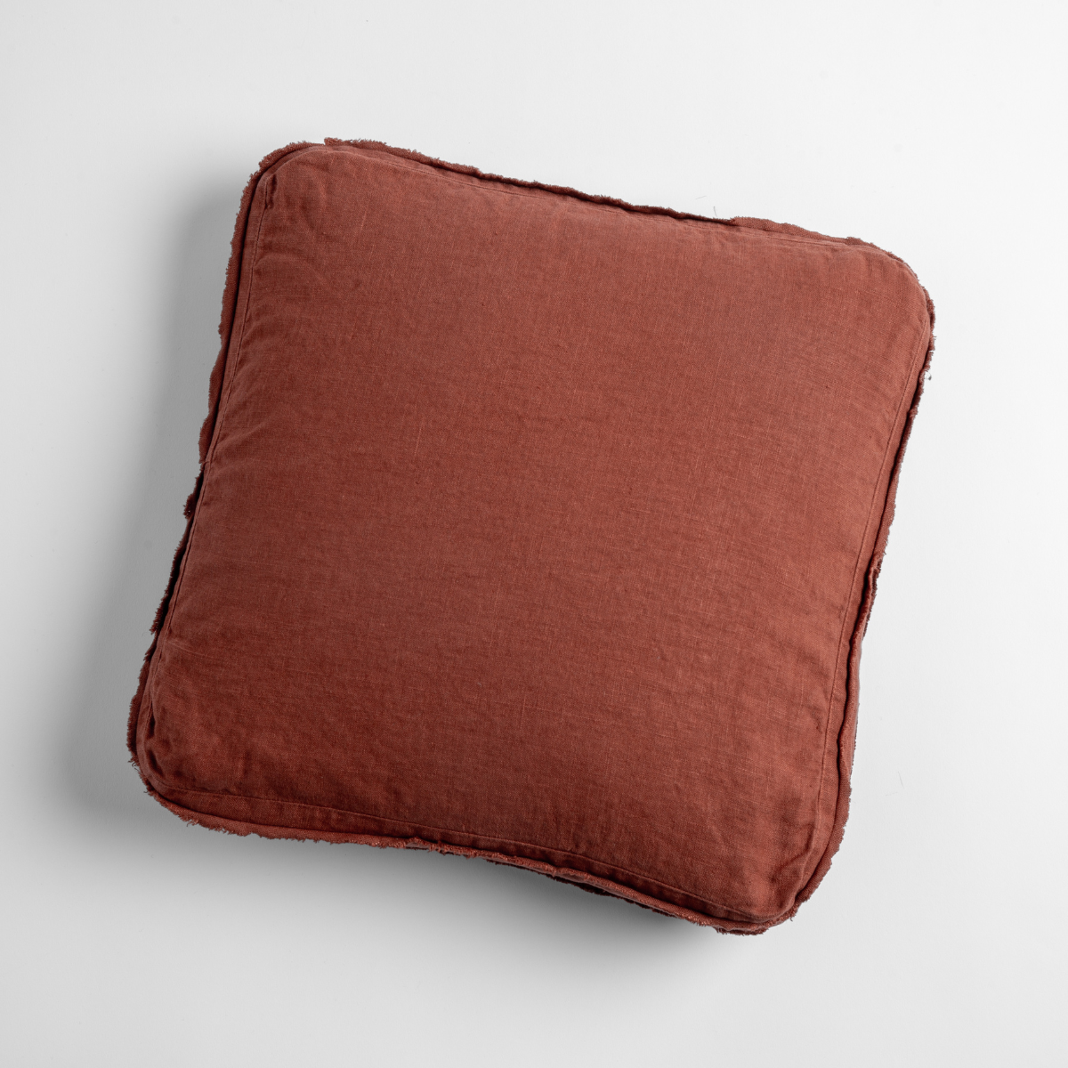 Austin throw pillow in Autumn, showing plump square profile with frayed linen edges.