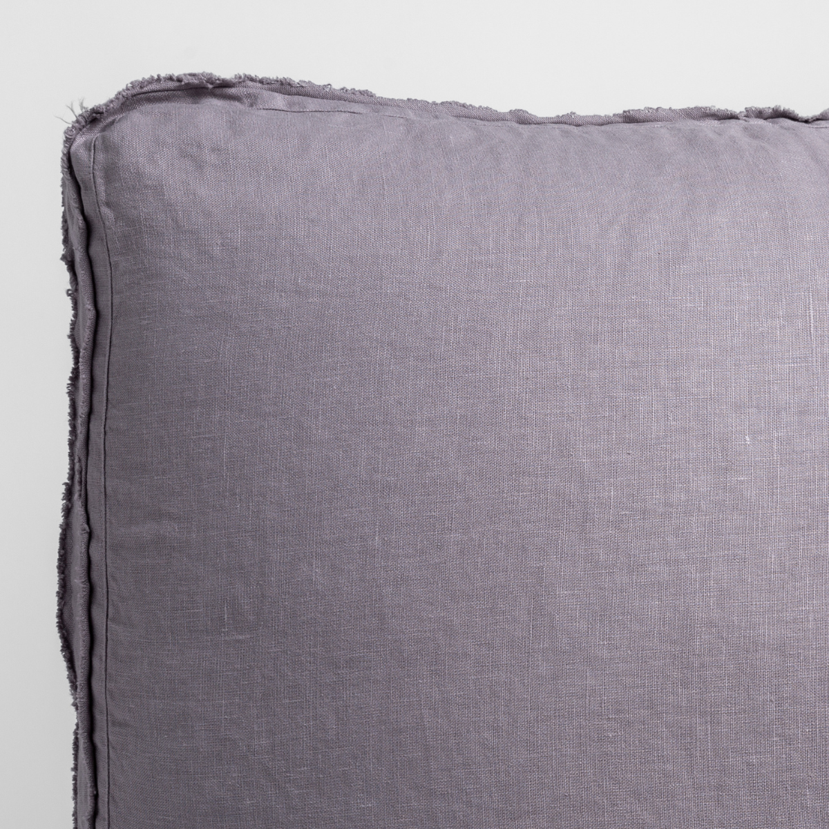 Close-up of French Lavender linen sham corner showing frayed edge trim detail.