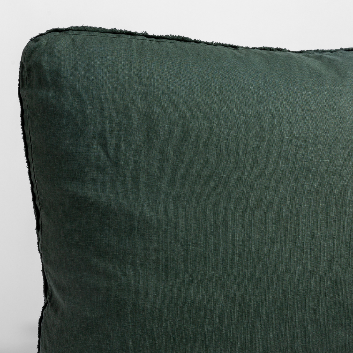Close-up of Juniper linen sham corner showing frayed edge trim detail.