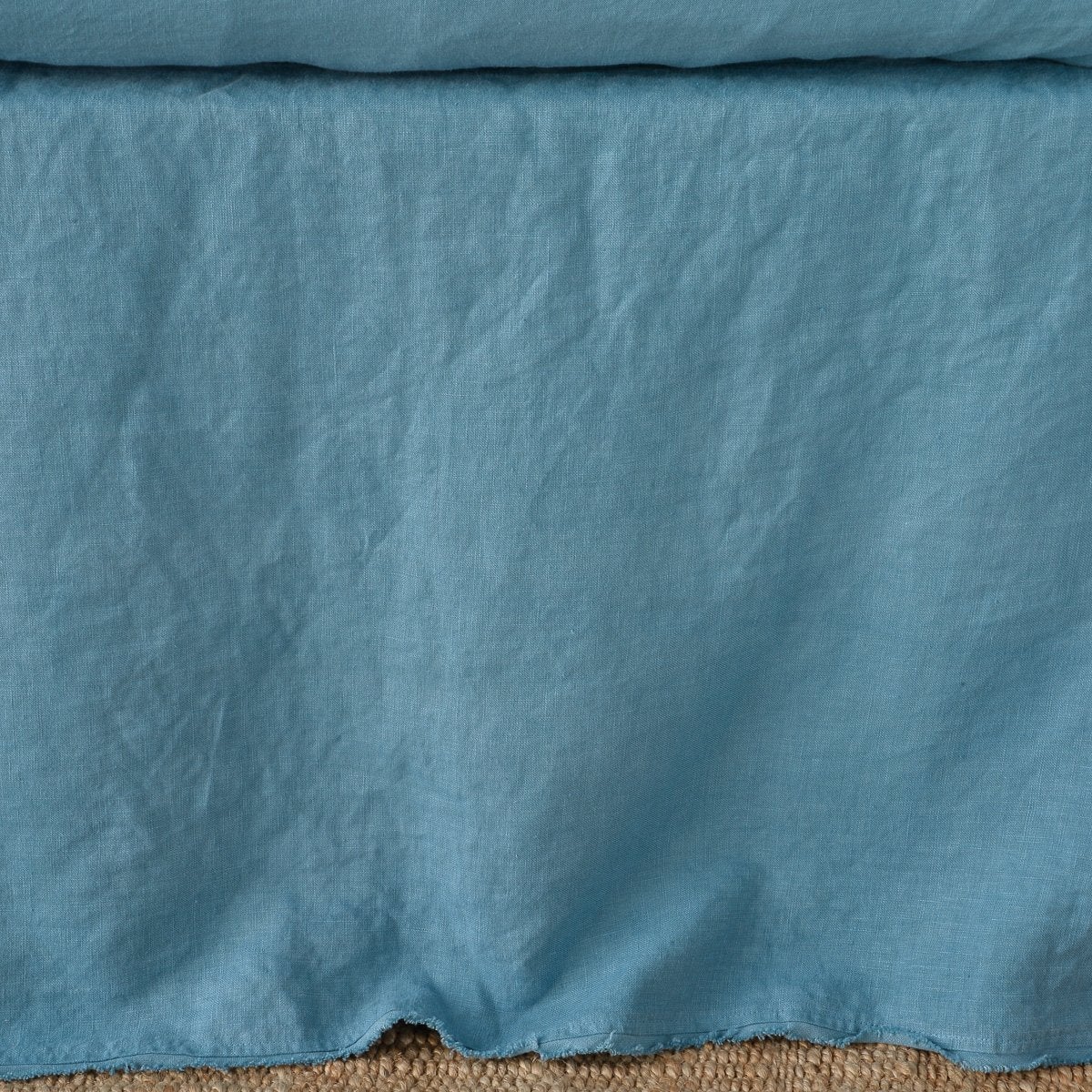 Bella Notte Austin bed skirt in Cenote, showing relaxed linen drape and natural creasing detail.