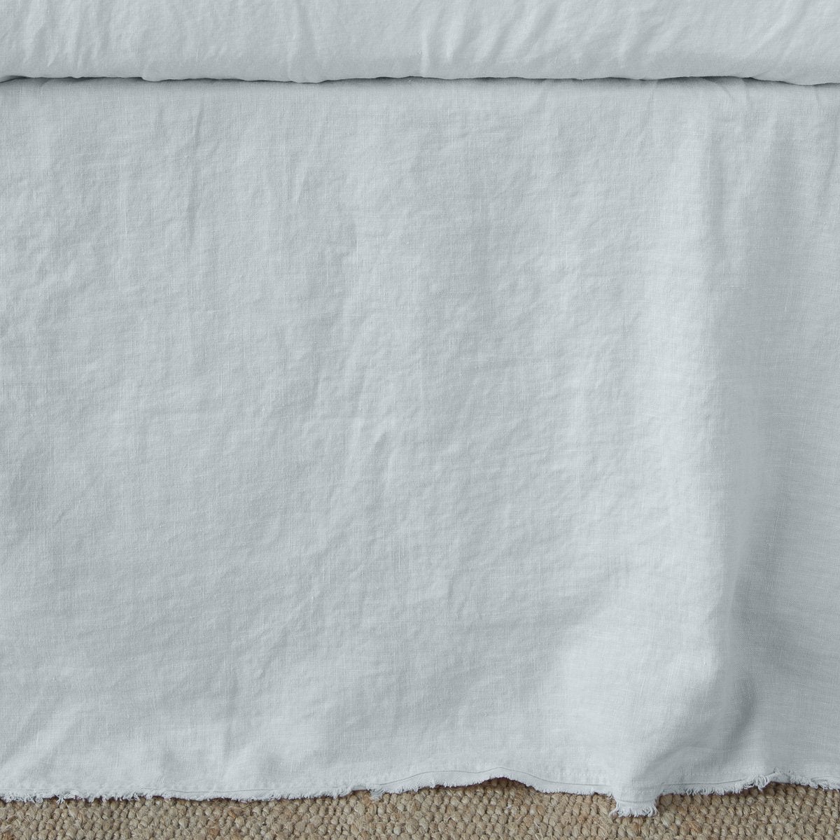 Bella Notte Austin bed skirt in Cloud, relaxed linen drape with raw hem detail.
