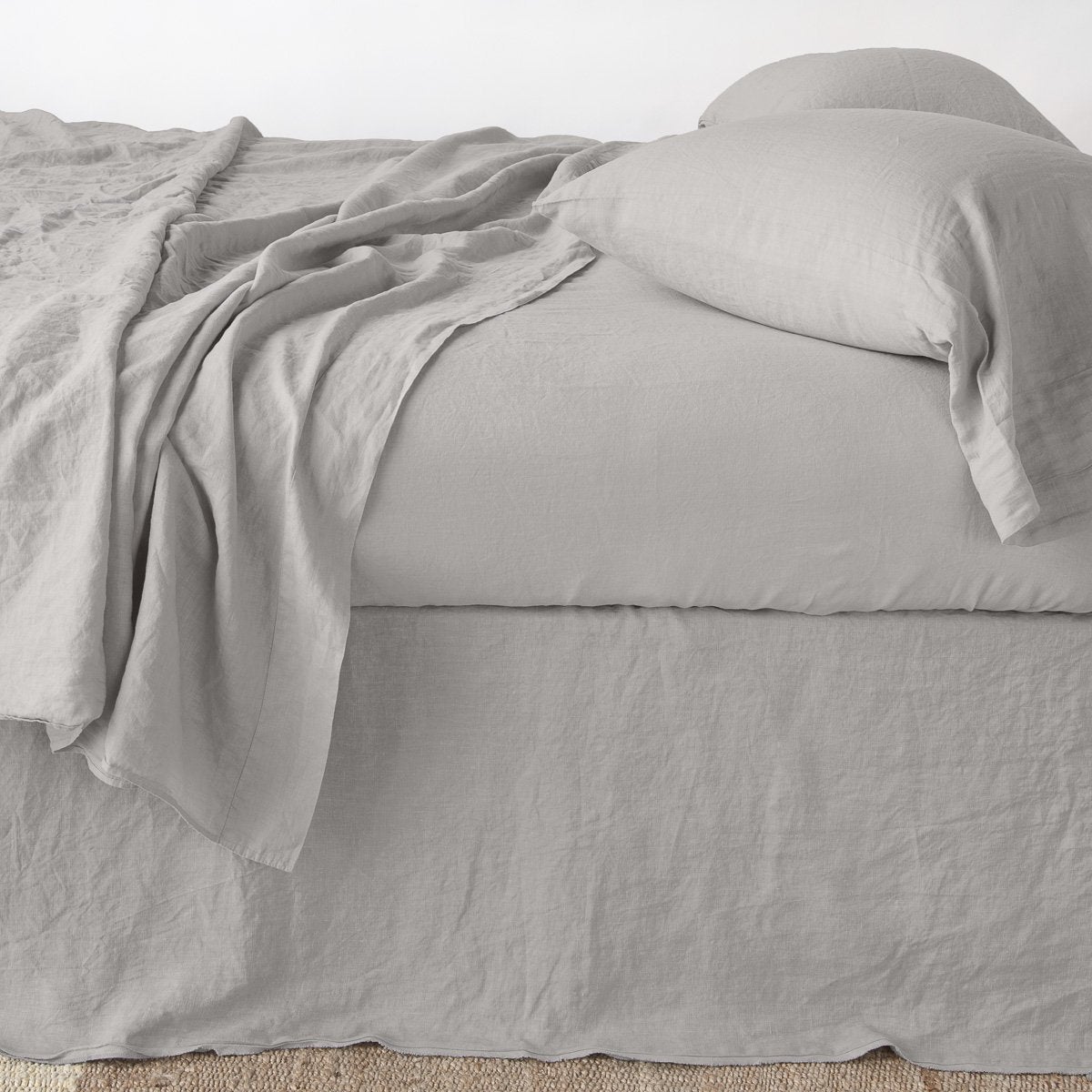 Bella Notte Austin bed skirt in Fog, shown on a styled bed with matching linen layers.