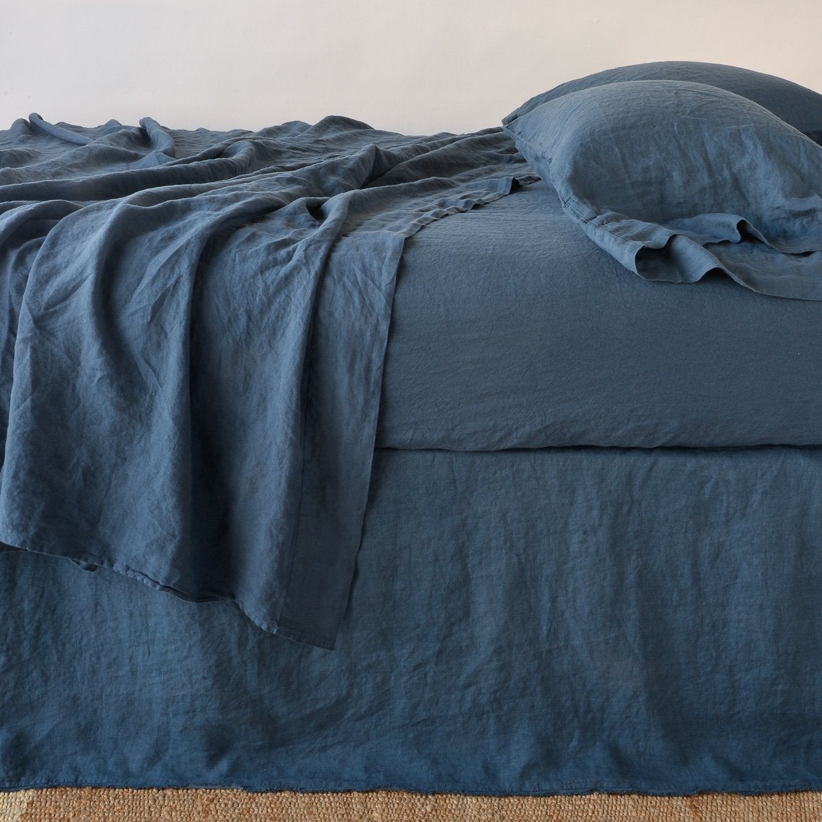 Midnight blue linen bed skirt styled on a bed with matching duvet and pillow.