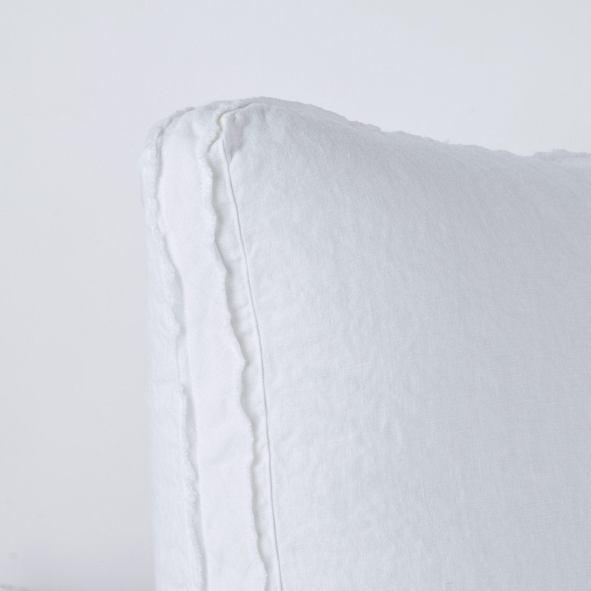Close-up of White Austin sham corner showing relaxed linen texture and frayed trim detail.