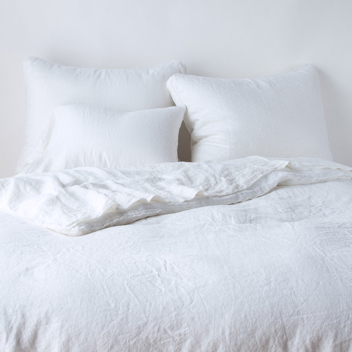 Bella Notte Austin sham in White, shown layered on a relaxed linen-draped bed.