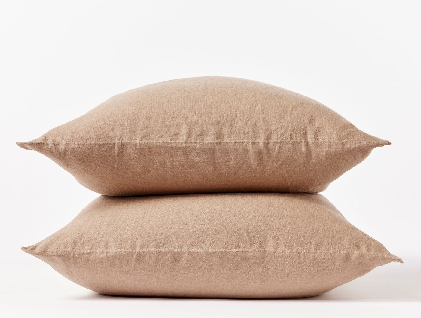 Two stacked Coyuchi Relaxed Linen pillowcases in warm tan, showing natural wrinkled texture.