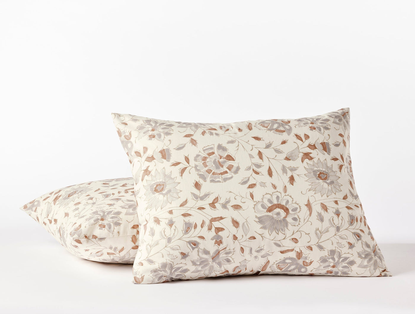 Close-up of two Coyuchi Flora Print shams stacked, ivory with terracotta and gray floral print.