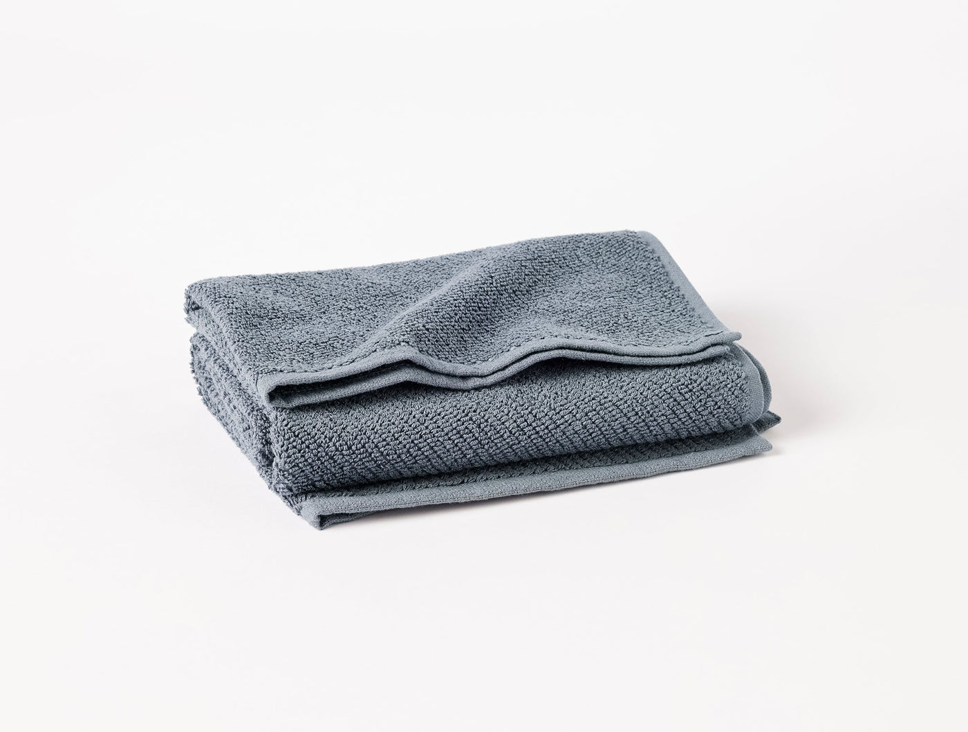 Close-up of folded slate blue Coyuchi Air Weight bath sheet showing textured waffle weave.