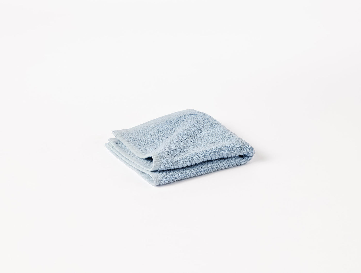 Coyuchi Air Weight wash cloth folded, shown in dusty blue terry against white background.