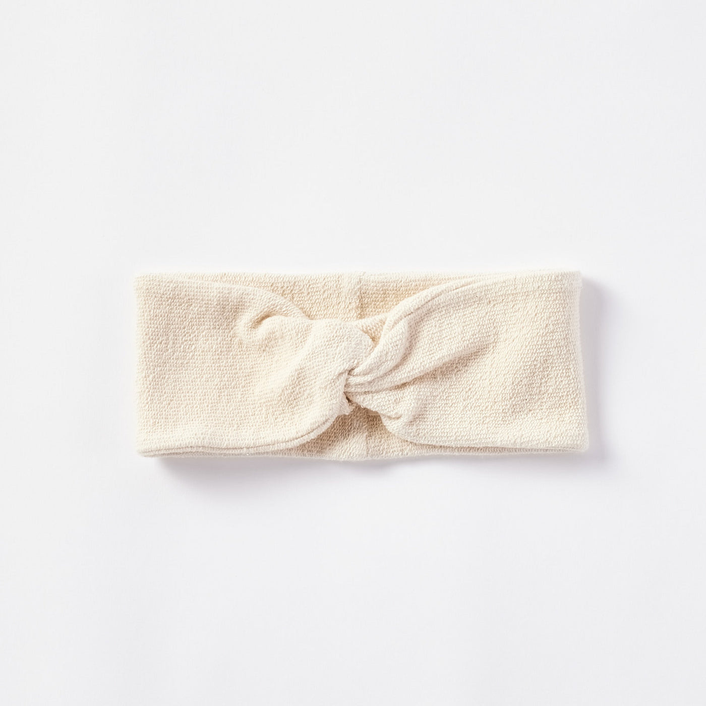 Coyuchi Bare headband in ivory terry cloth with a knotted front detail, flat lay.