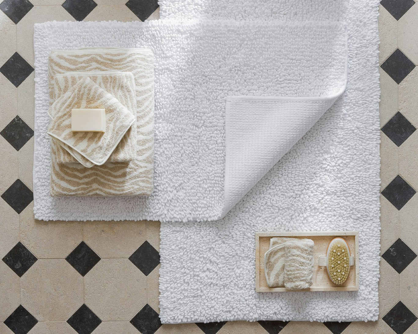 White bath mat with textured design on a tiled floor