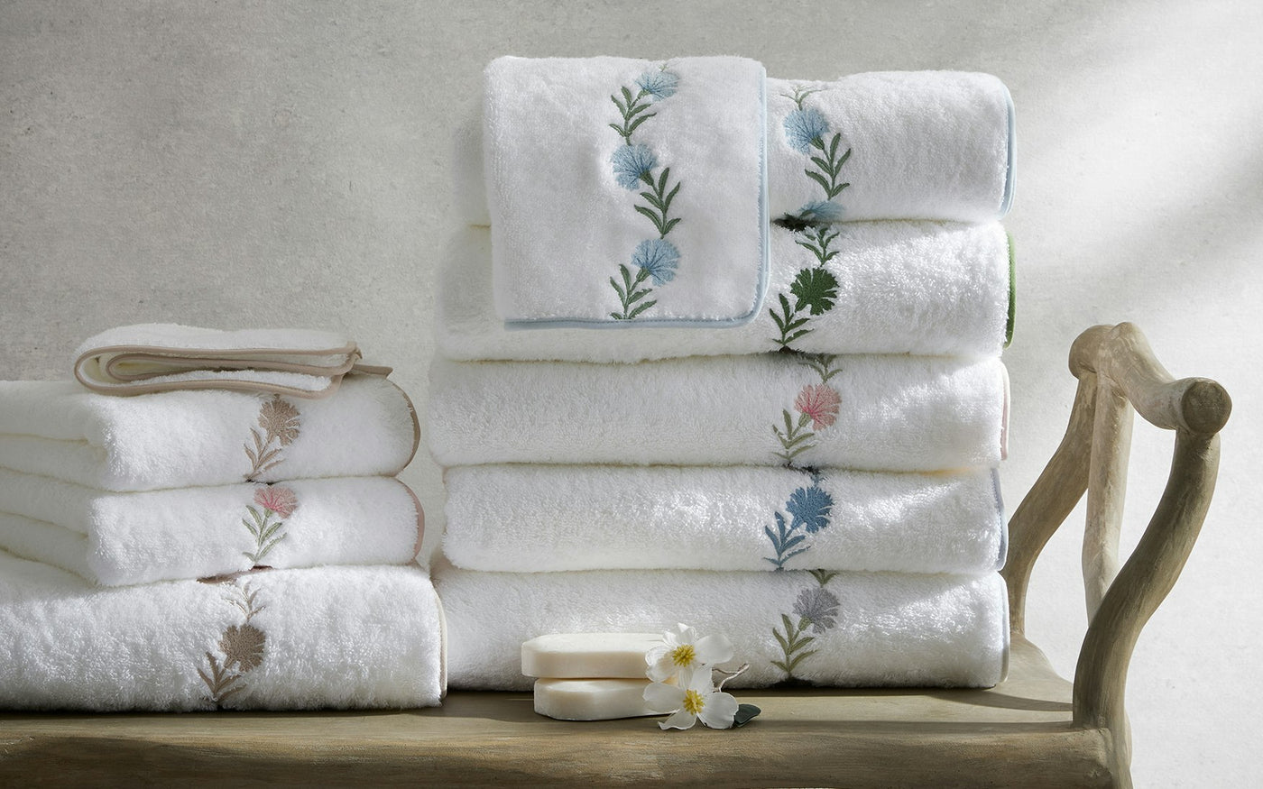Close-up of Matouk Daphne white bath towels stacked, showing floral embroidered border detail.
