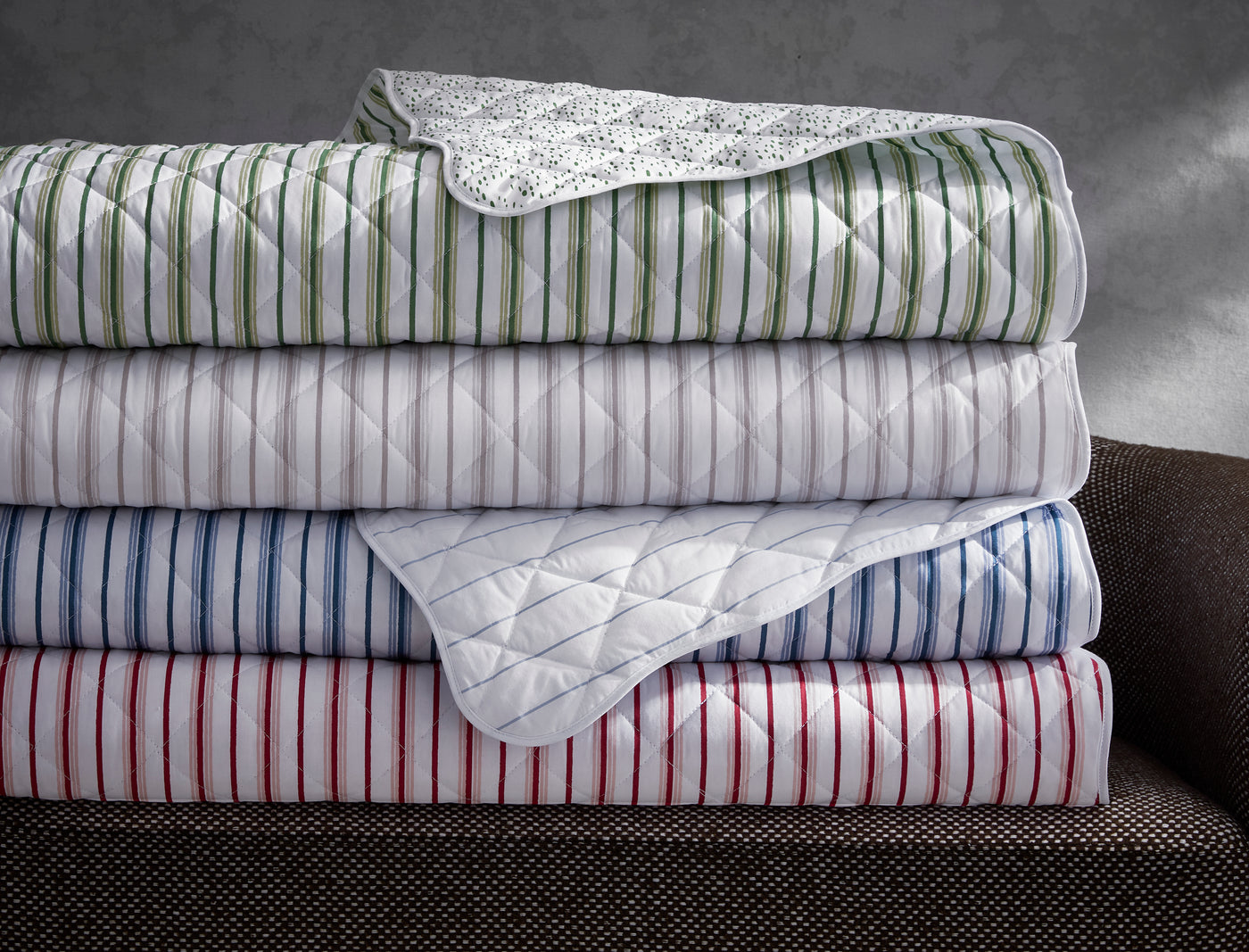 Close-up of stacked Calypso quilted shams in green, blue, and red stripe colorways.