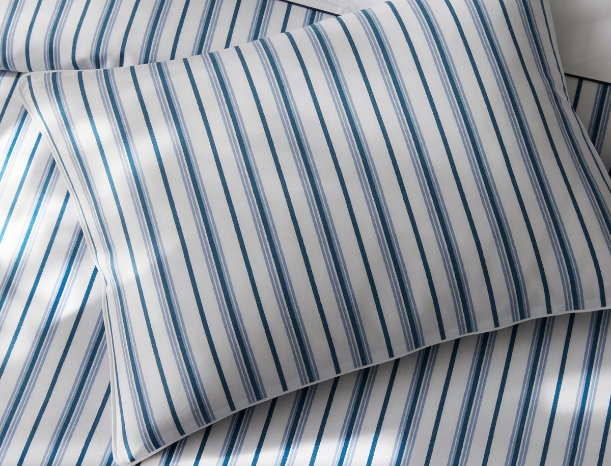 Close-up of Matouk Calypso pillowcases in blue and ivory woven ticking stripes.