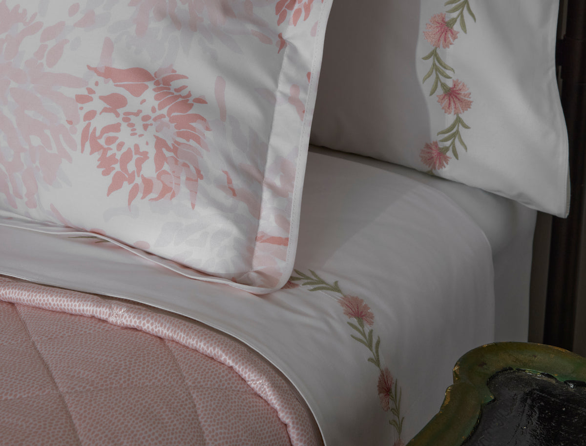 Close-up of Matouk Chrysanthemum pillowcase in blush, floral embroidery along sheet border.
