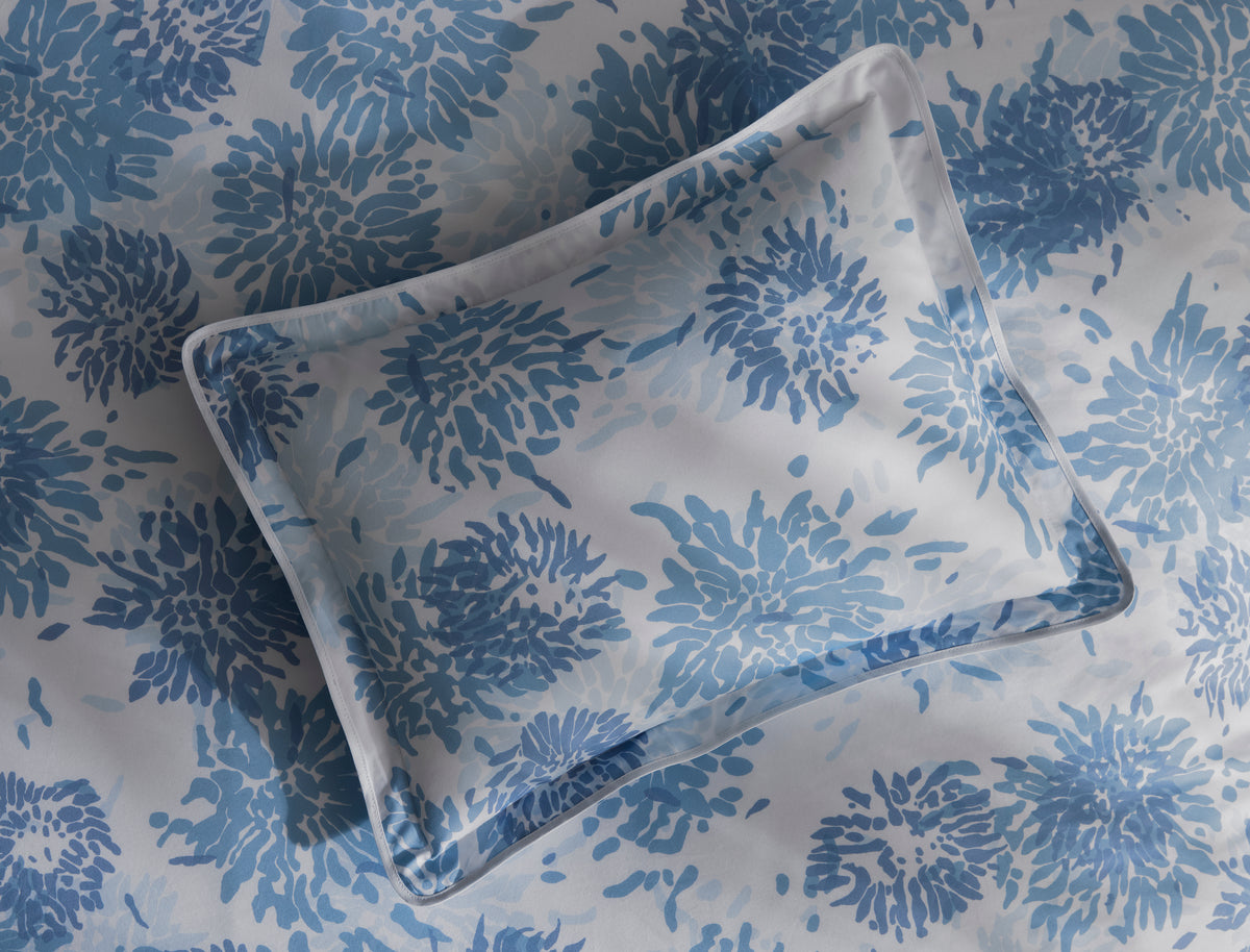 Close-up of Matouk Chrysanthemum pillowcase with blue floral print and piped border.