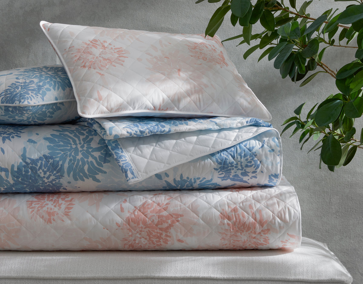 Close-up of Matouk Chrysanthemum quilted shams stacked with matching quilt in blush and sky.