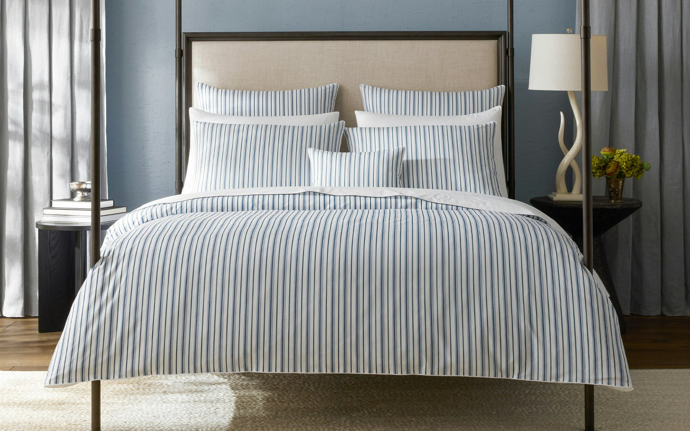 Close-up of Matouk Calypso sham with blue and white ticking stripes on styled bed.