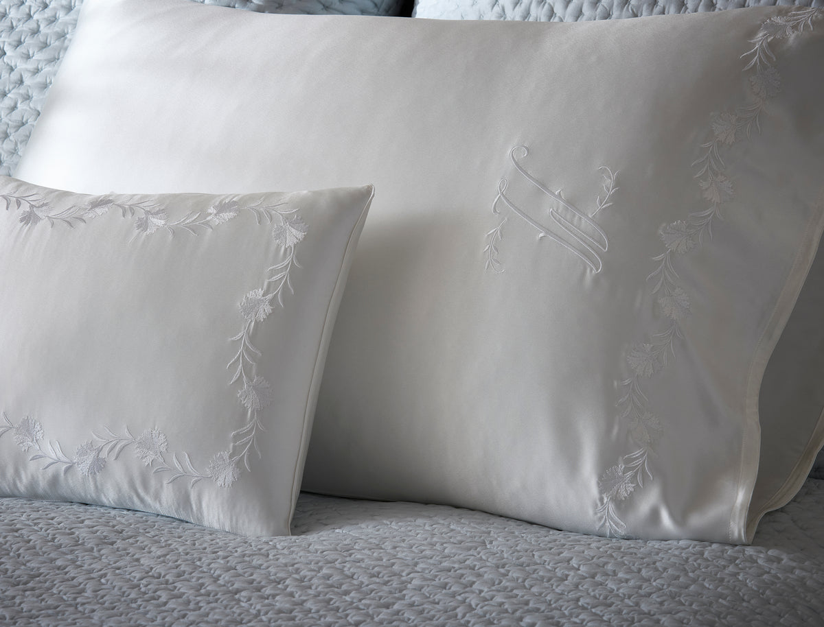 Close-up of ivory silk pillowcases with tonal floral vine embroidery.