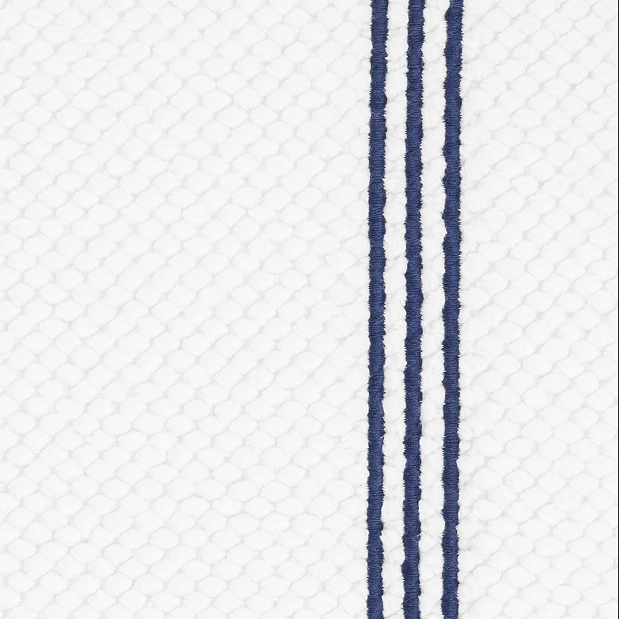 Close-up of navy double-stripe detail on white waffle-textured bath rug.