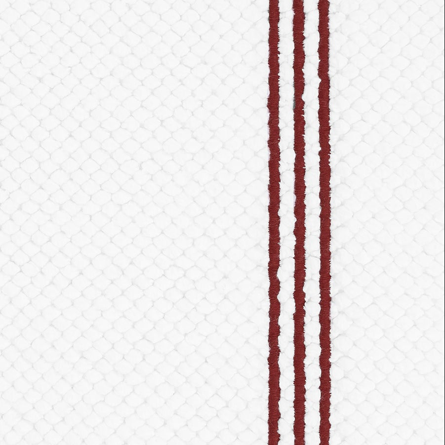 Close-up of Matouk Bel Tempo bath rug showing crimson double stripes on white waffle weave.