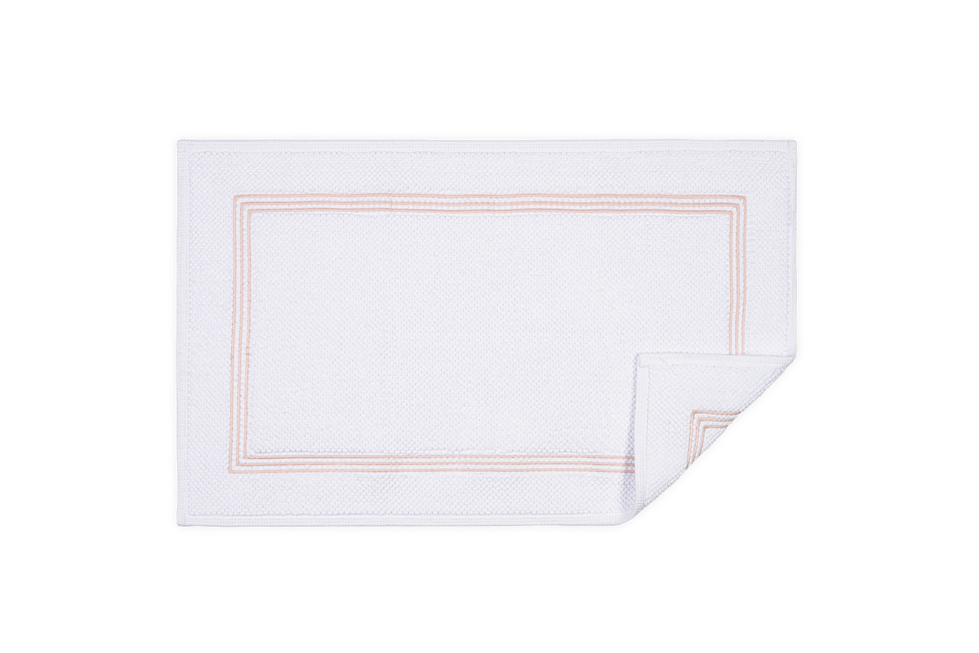 Corner detail of Matouk Bel Tempo bath rug showing blush double-stripe border on white cotton.