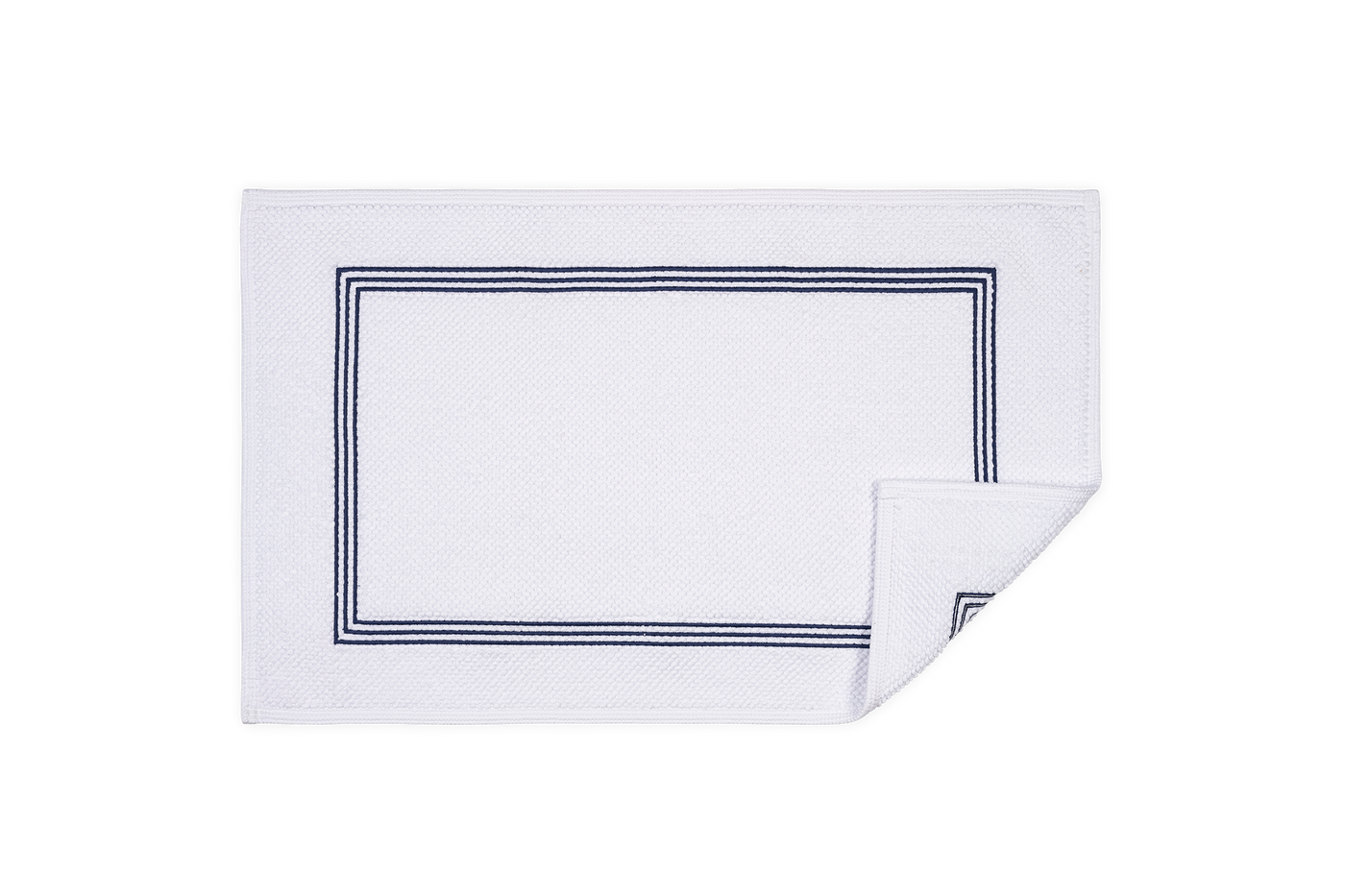 Corner detail of Matouk Bel Tempo white bath rug with navy double-stripe border.