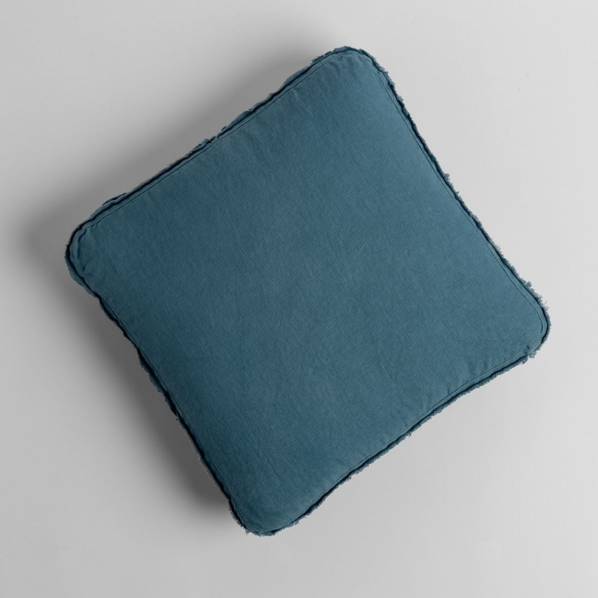 Overhead view of Bella Notte Austin throw pillow in Cenote with frayed linen edges.