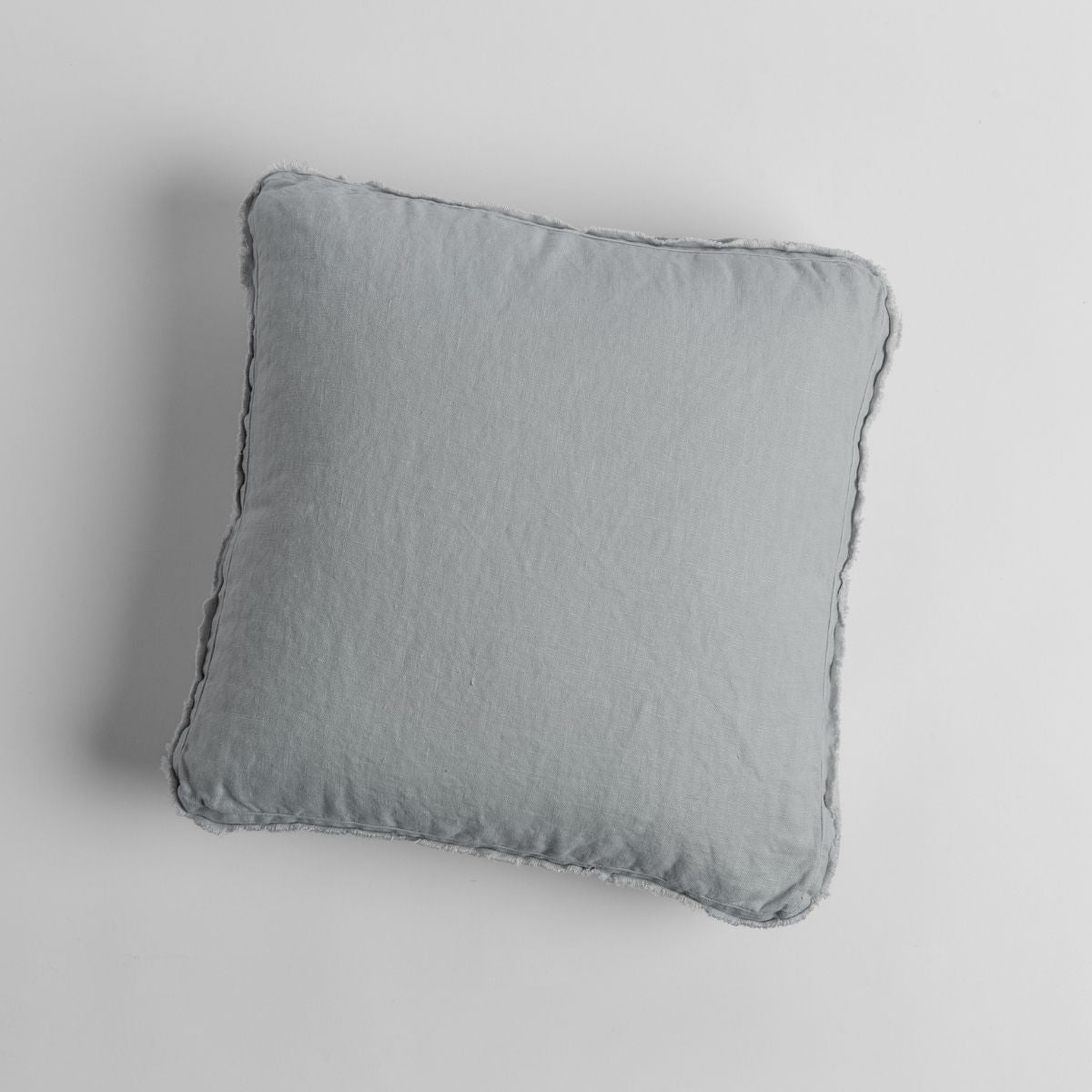 Overhead view of the Austin throw pillow in Cloud, showing relaxed linen texture and flange edge.