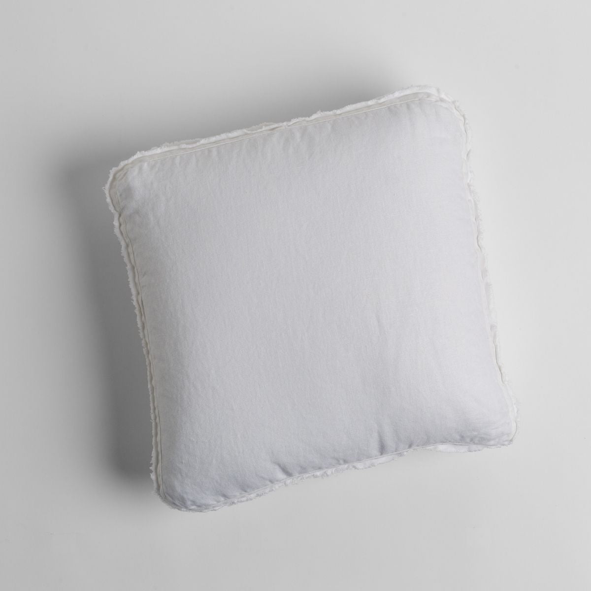 Bella Notte Austin throw pillow in White with soft linen texture and frayed edges, overhead view.