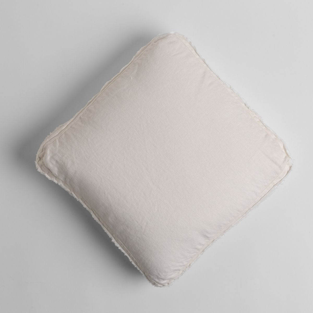 Winter White Austin throw pillow angled overhead view, showing frayed linen edges.