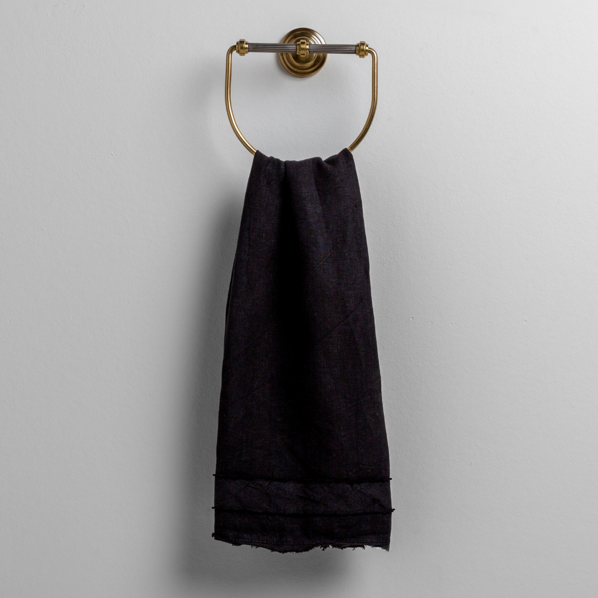 Corvino guest towel draped over an antique brass ring holder, showing fringe hem detail.