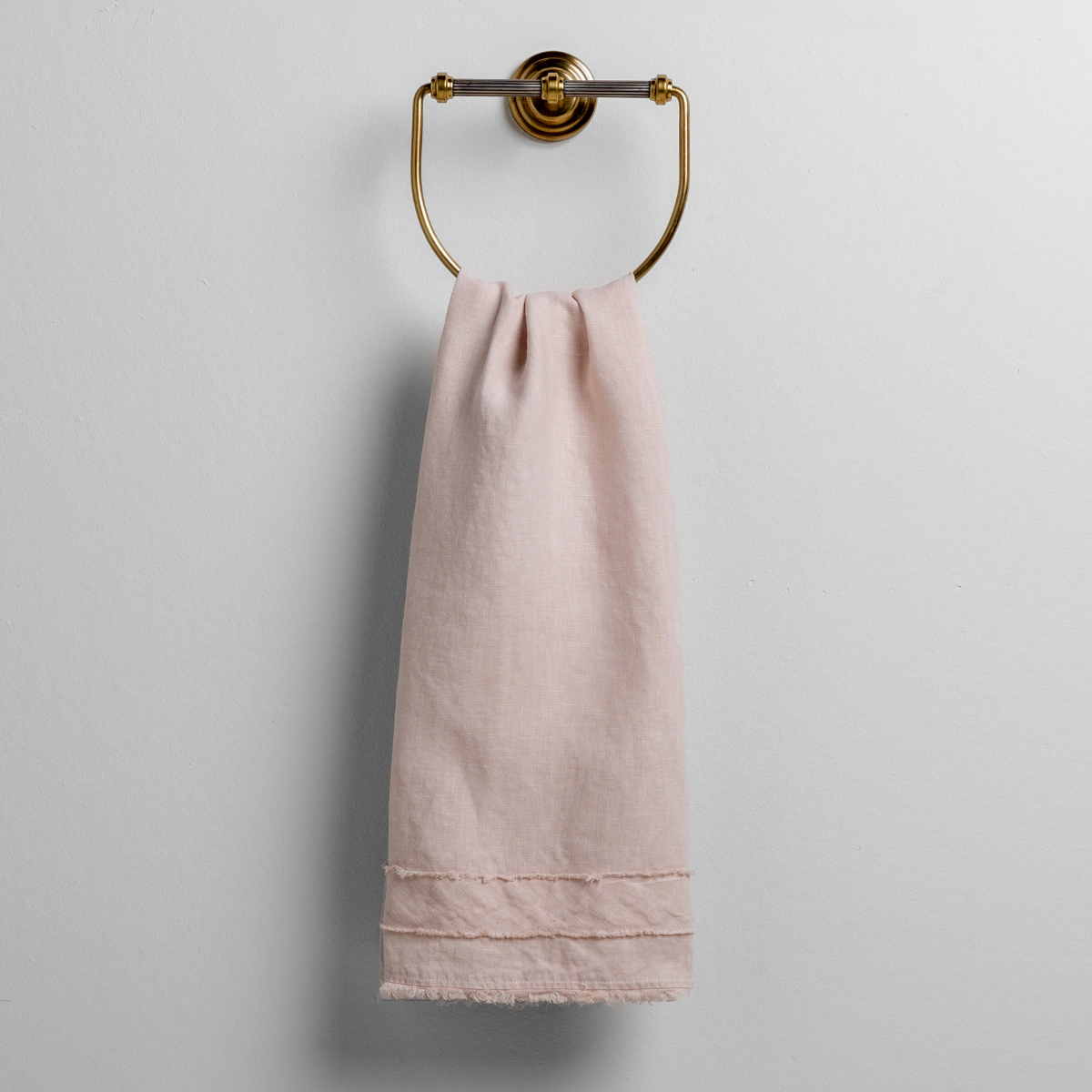 Pearl Austin guest towel hung on brass ring, showing fringe hem detail.