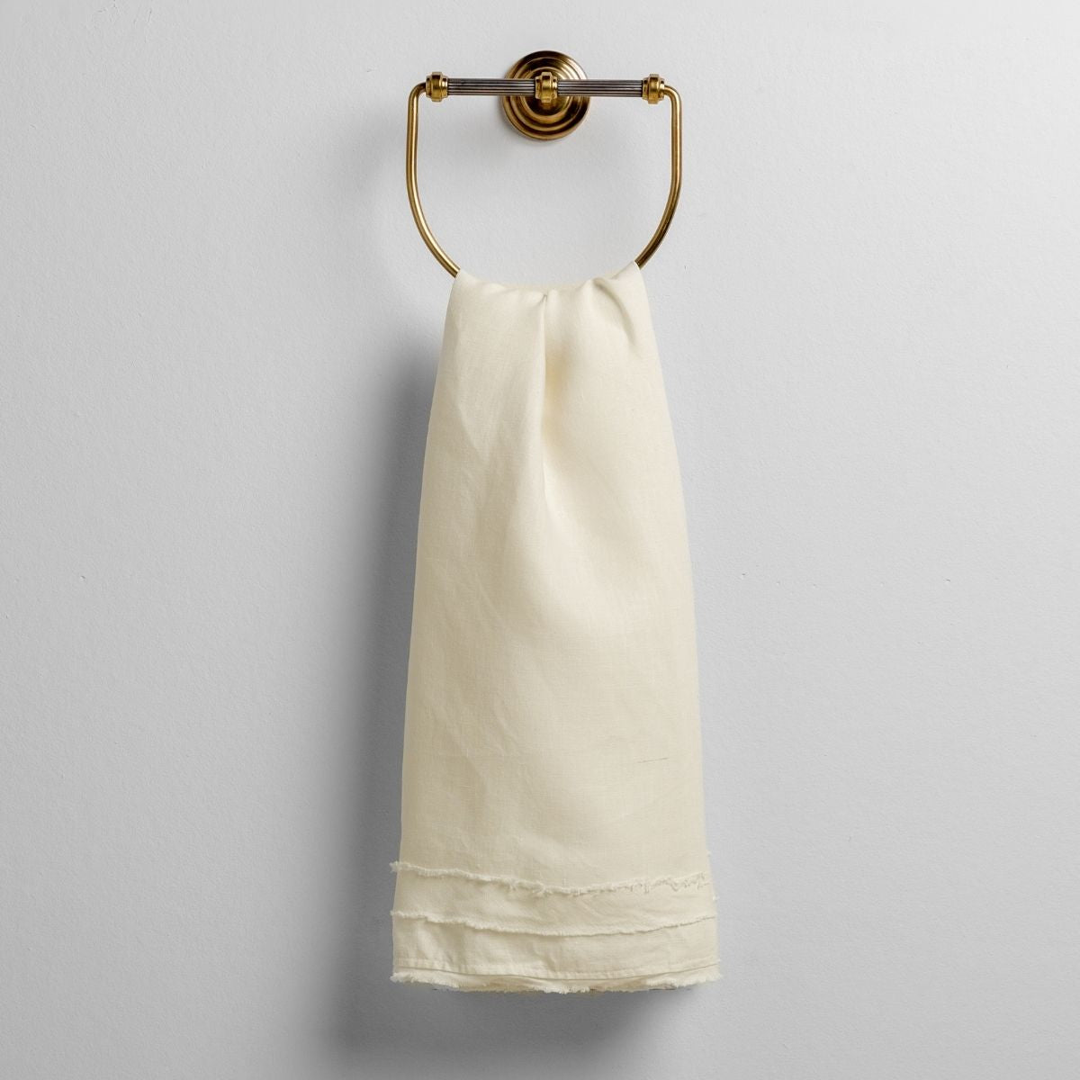 Bella Notte Austin guest towel in Winter White draped over a brass ring holder, fringe hem detail.