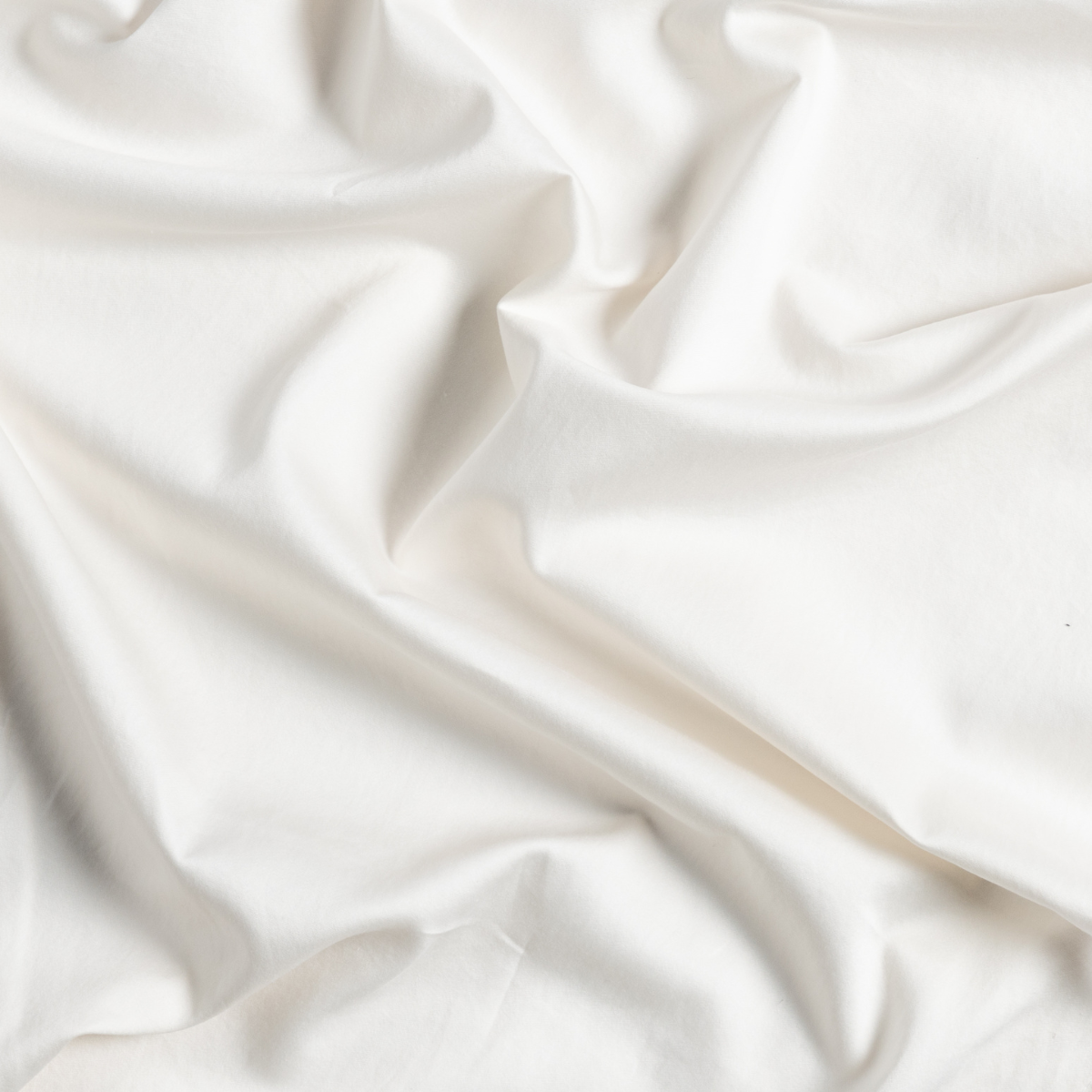 Close-up of draped Natural Bella Notte Bria flat sheet showing silky sheen and soft folds.