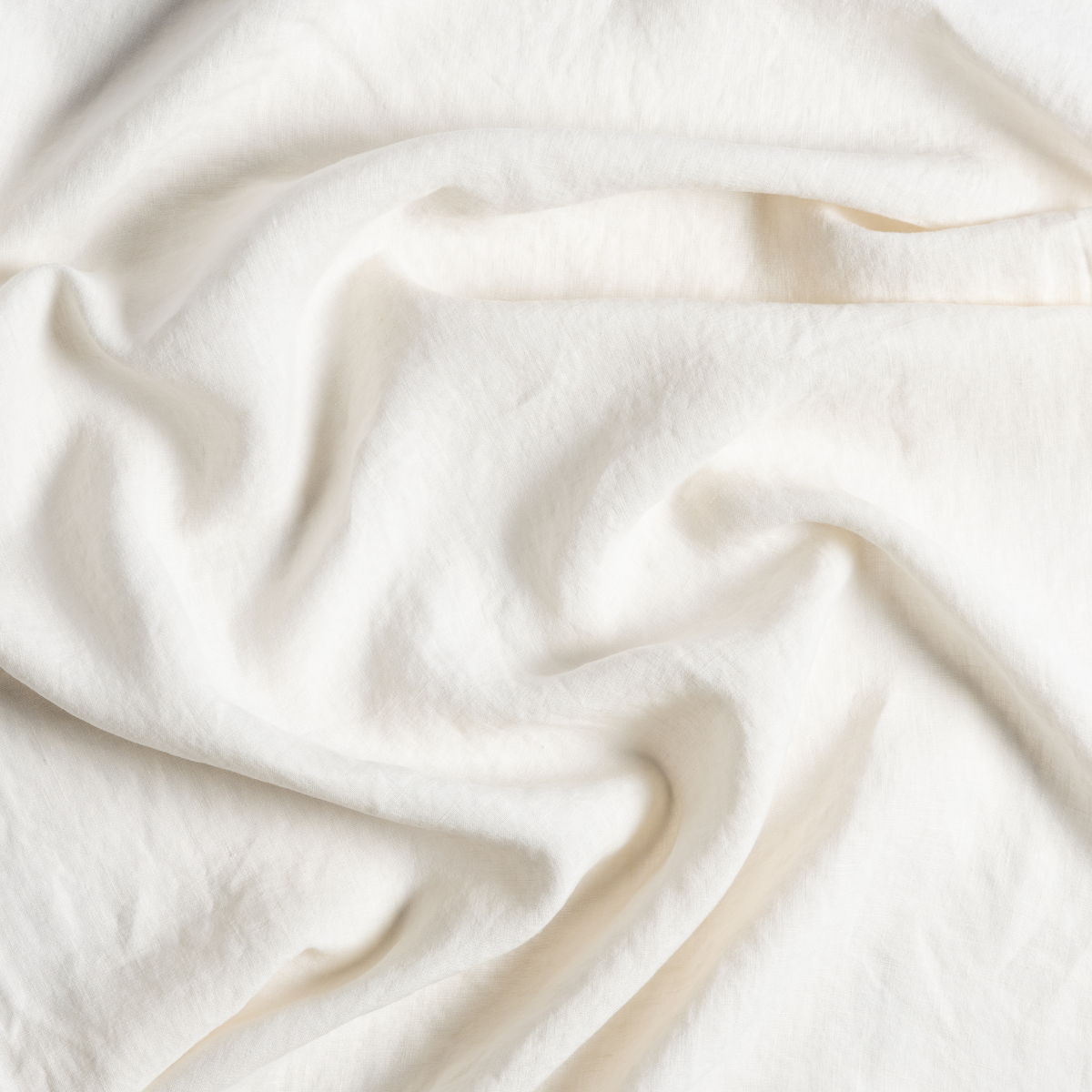 Close-up of Bella Notte Linen crib skirt in Natural, showing soft draped fabric texture.