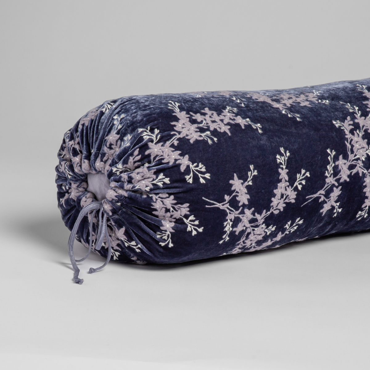 French Lavender velvet bolster pillow with floral embroidery and gathered end detail.