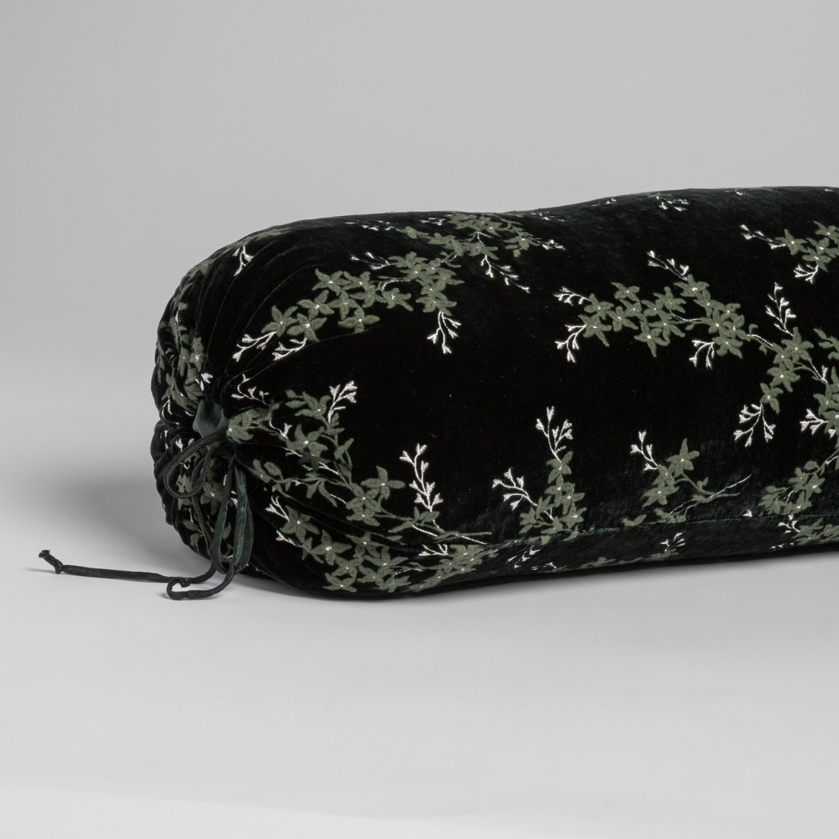 Black velvet Bella Notte Lynette bolster with Juniper floral vine embroidery and tassel end detail.