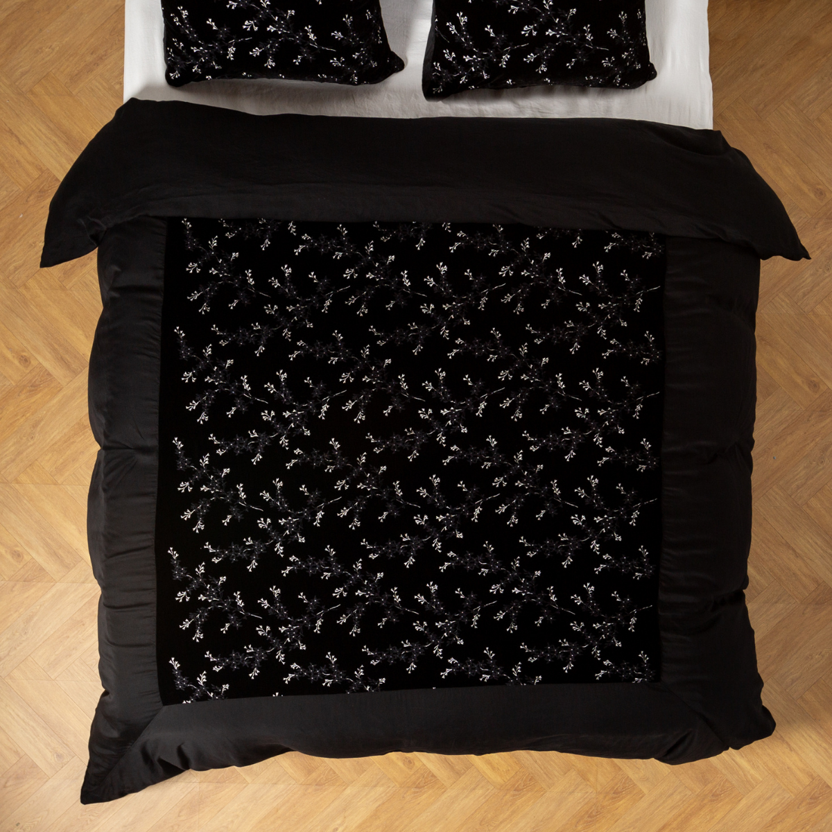 Overhead view of Corvino duvet cover with floral-embroidered center panel on black bedding.