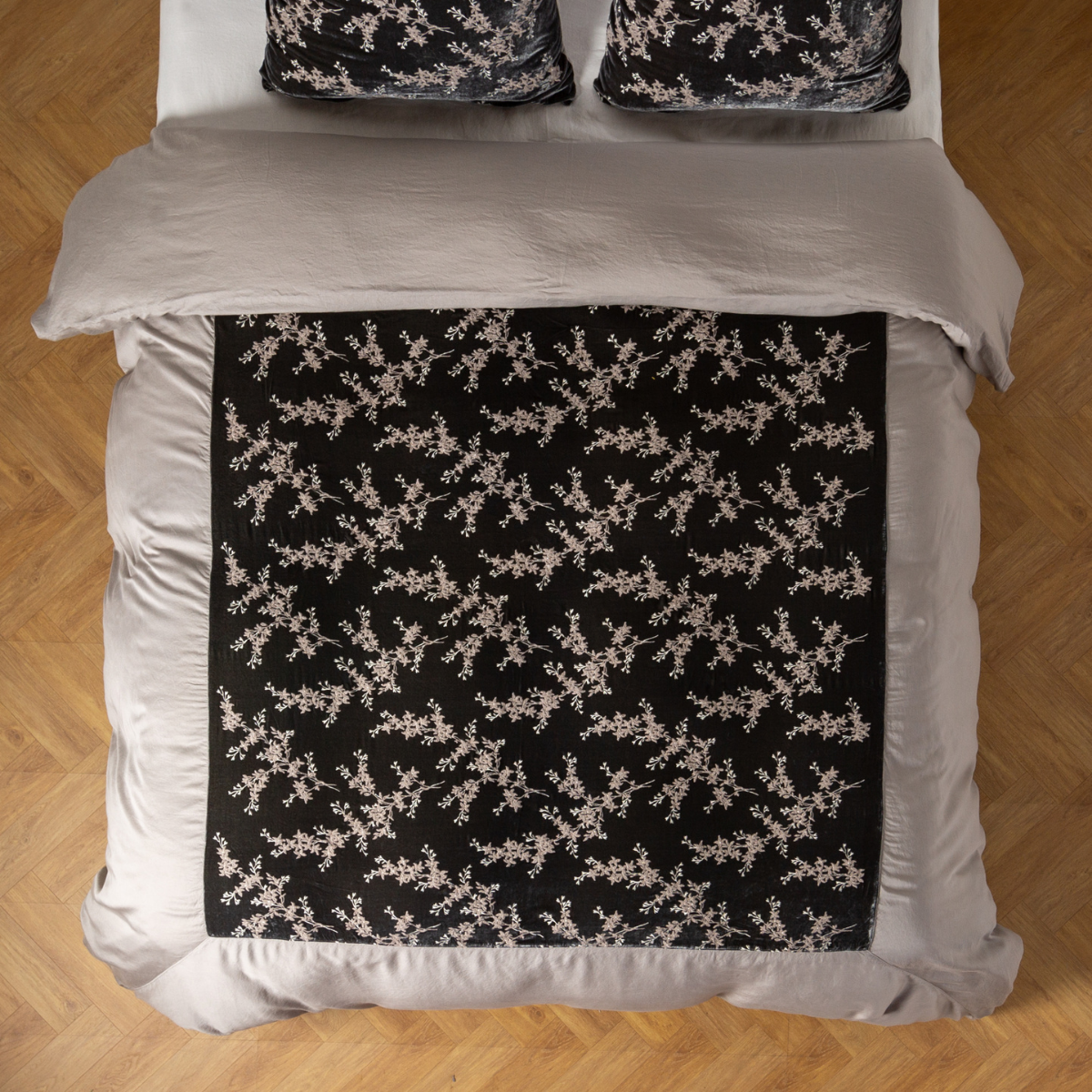 Overhead view of Fog duvet cover with black floral panel, styled on a bed with matching pillows.