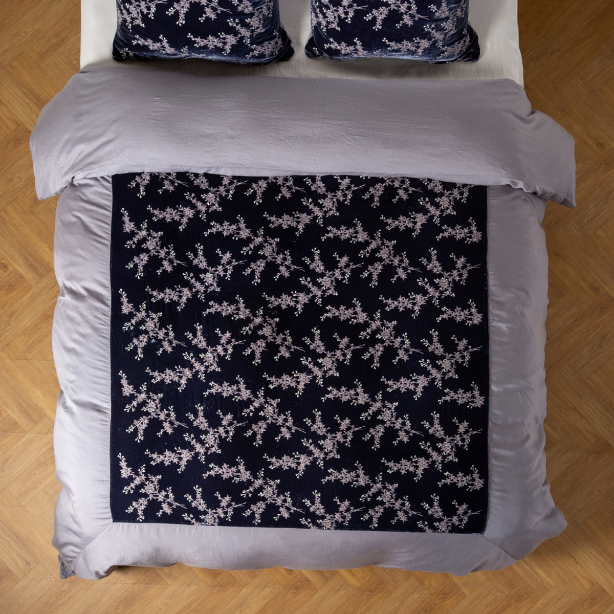 Overhead view of French Lavender duvet with dark floral-embroidered center panel on styled bed.