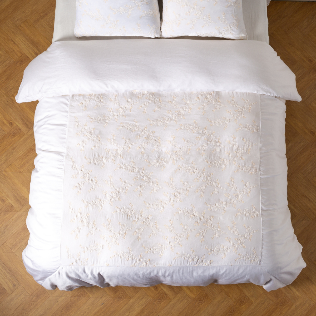 Bella Notte Lynette Luxe duvet cover in White with tufted floral pattern, styled on bed, overhead view.